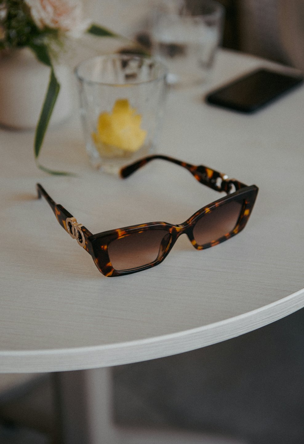 Tortoiseshell sunglasses resting on a light wooden table.
