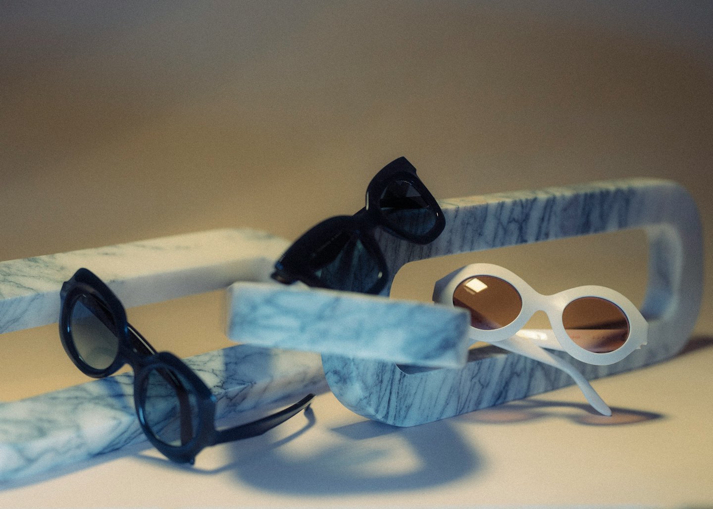 Stylish sunglasses displayed on marble geometric blocks.