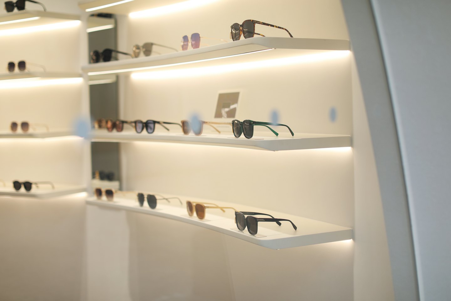 Stylish sunglasses displayed neatly on clean white retail shelves.