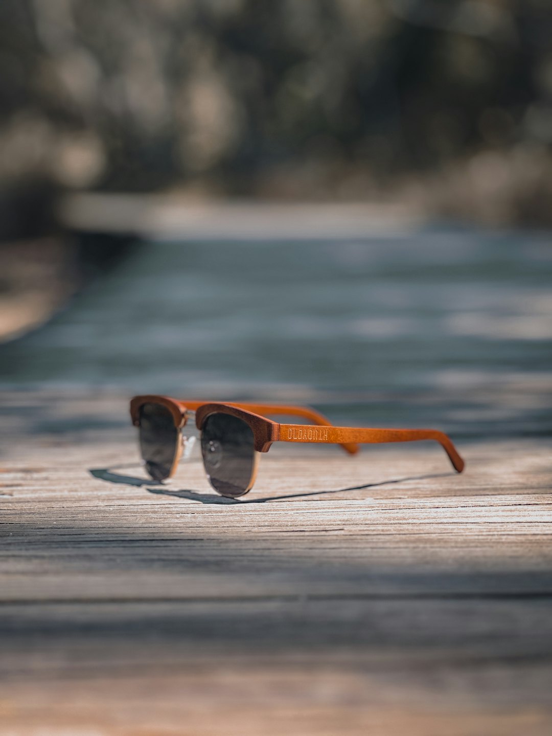 Brown wooden sunglasses with dark lenses sit on weathered planks.